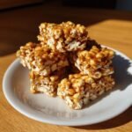 A stack of gooey, caramel-coated popcorn desserts bars resting on a small white plate.