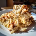 A fork lifting a bite of creamy Cheesy Chicken Orzo showing long, stretchy melted cheese strands.