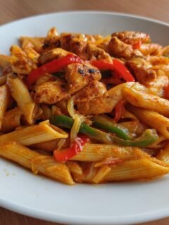 A close-up of a serving of creamy Chicken Fajita Pasta with seasoned chicken pieces and colorful bell peppers.