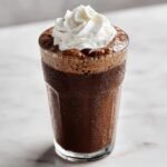 A tall, frosty glass filled with a dark brown Coffee Milkshake, topped with a swirl of whipped cream.