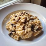 A close-up of creamy mushroom risotto served in a white bowl, showcasing the rich texture central to great Risotto Recipes.
