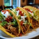 Close-up of three crispy tacos filled with shredded chicken, lettuce, sour cream, and salsa, perfect for quick Street Food Recipes.
