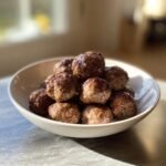 A white bowl piled high with glistening, browned meatballs, showcasing one of the many amazing Meatball Recipes.