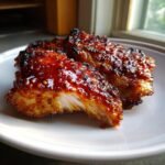 Close-up of sticky, caramelized pork pieces coated in a vibrant red Gochujang glaze, perfect for Gochujang Recipes.