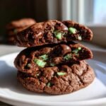 Close-up of three stacked Chocolate Mint Chip Cookies, showing the gooey, soft center with melted chocolate chips and bright green mint pieces.