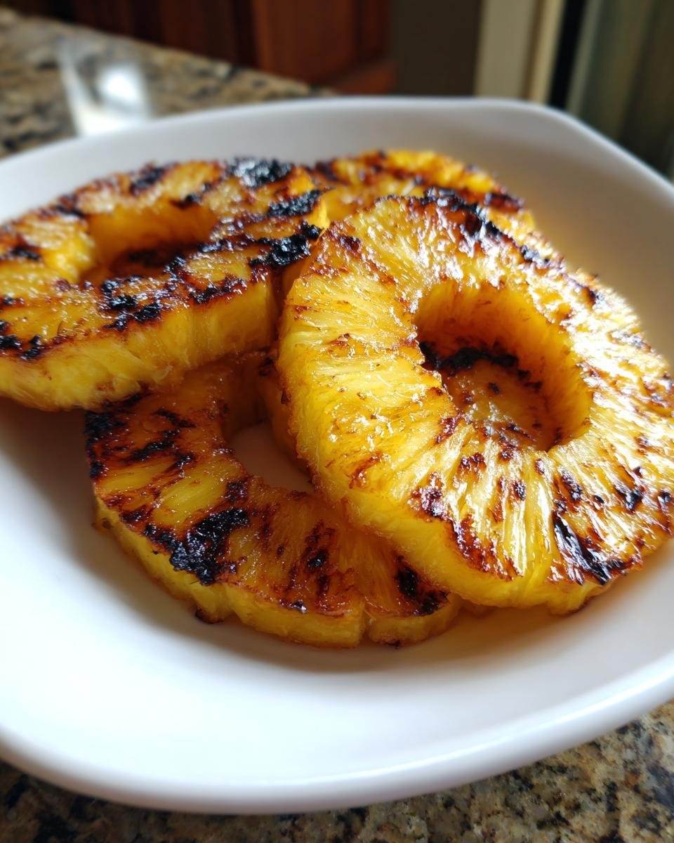 Close-up of three golden, caramelized Grilled Pineapple rings served in a white bowl.