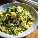 Close-up of fluffy couscous mixed with fresh chopped parsley and seasoning in a white bowl, perfect for quick couscous recipes.