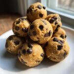 A close-up stack of delicious No Bake Cookie Dough Bites loaded with mini chocolate chips on a white plate.