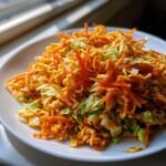 A close-up of a serving of Ramen Noodle Asian Salad featuring crunchy noodles, shredded carrots, and cabbage tossed in dressing.