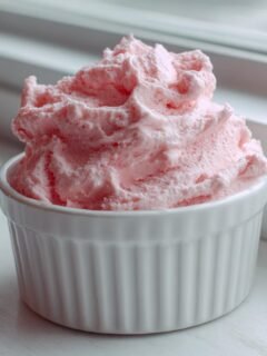 Close-up of light pink, airy Raspberry Mousse served in a small white fluted ramekin.