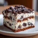 Close-up of a layered slice of the Robert Redford Dessert featuring white cream and dark chocolate cookie pieces.