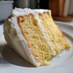 Close-up of a moist slice of yellow cake with thick white frosting, perfect for Mothers Day Cakes.