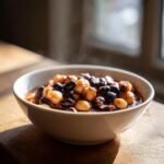 A close-up of a steaming bowl filled with hominy recipes stew, featuring light hominy kernels and dark beans in a rich sauce.