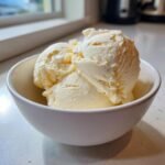 Three scoops of creamy vanilla ice cream served in a small white bowl, perfect for low-calorie Ice Cream Desserts.