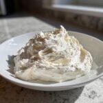 A mound of fluffy, white whipped horseradish cream served in a shallow white bowl.