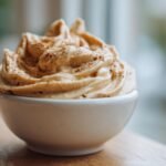 Close-up of creamy, whipped Monkey Butter topped with a sprinkle of cinnamon, served in a small white bowl.