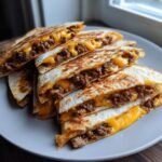 A stack of golden-brown Cheeseburger Quesadillas filled with seasoned ground beef and melted cheddar cheese.