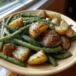 Roasted potatoes and green beans seasoned with herbs, representing Country Ranch Green Beans And Potatoes.