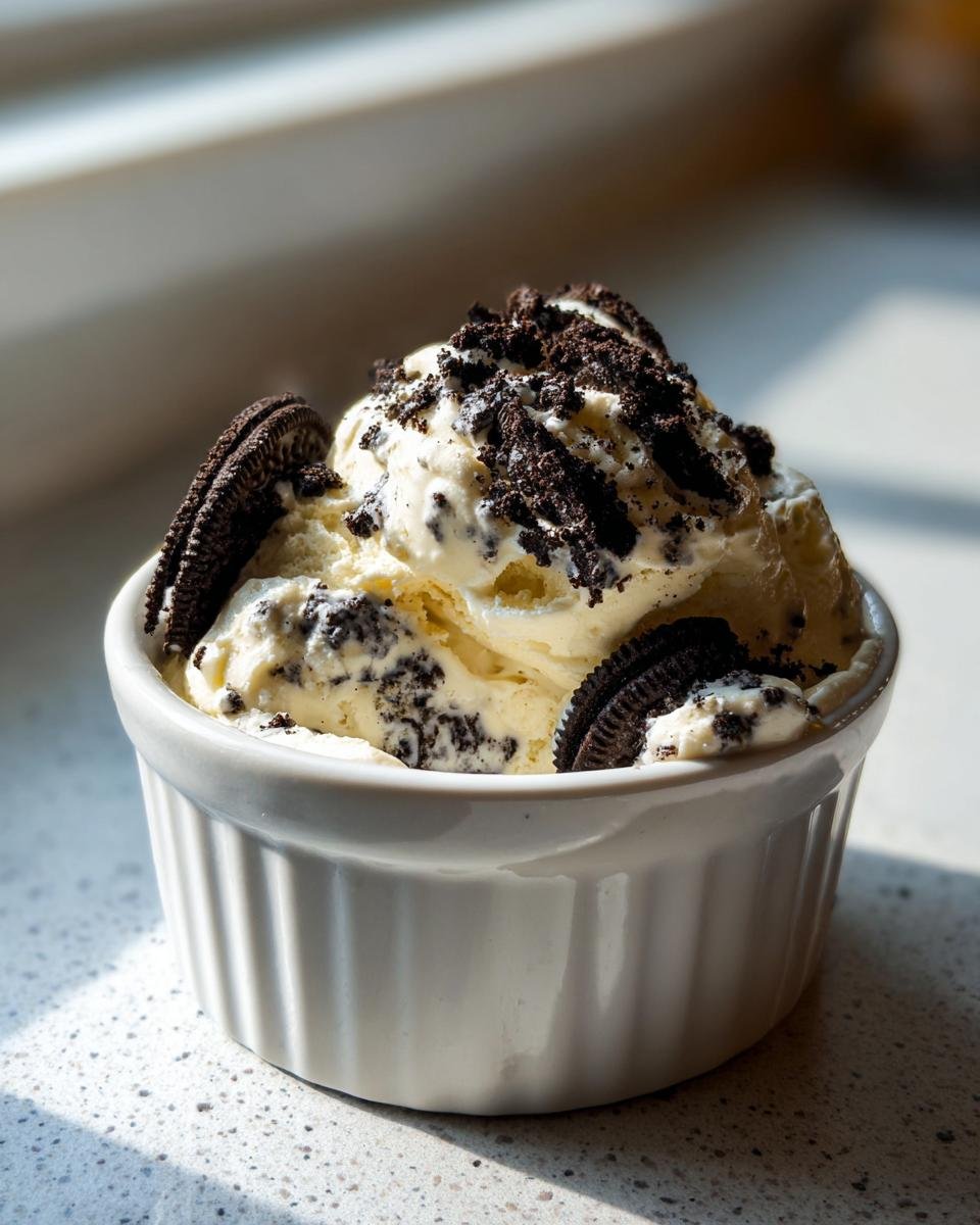 A serving of creamy Oreo Pudding topped with crushed cookies and whole Oreo pieces in a white ramekin.