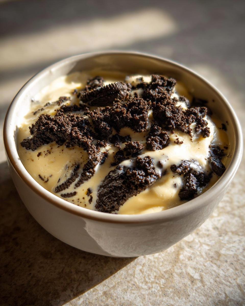 Close-up of creamy vanilla Oreo Pudding topped generously with crushed dark chocolate Oreo cookies.