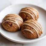 Three soft Gingerbread Latte Cookies drizzled with a light brown coffee-flavored glaze, resting on a white plate.