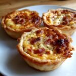 Close-up of three freshly baked Mini Quiche with golden crusts and cheesy, savory filling.