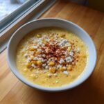 A creamy bowl of Mexican Street Corn Soup topped with crumbled white cheese and chili powder.