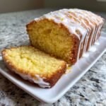 A slice cut from a golden Pina Colada Pound Cake topped with a white vanilla glaze and zest.