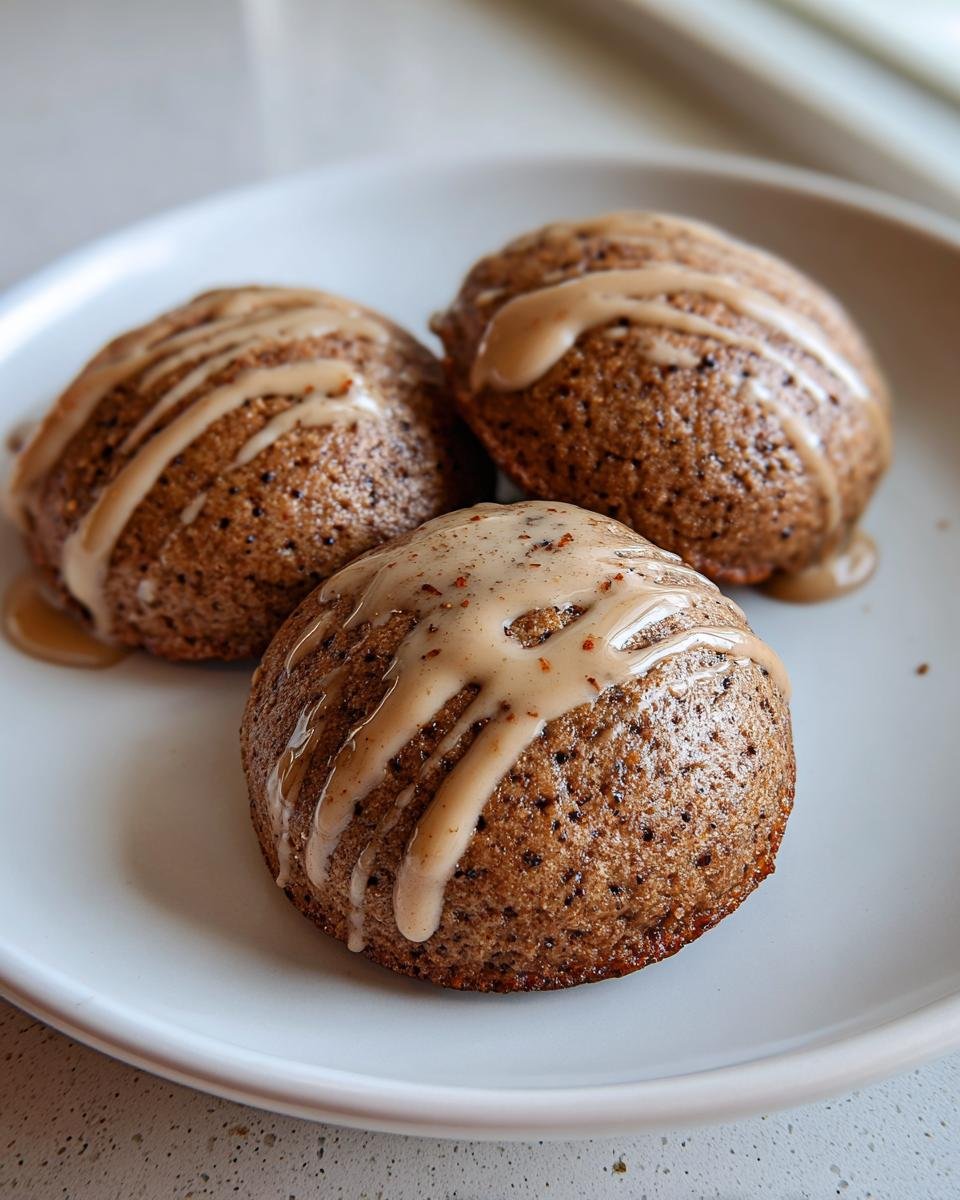 Three freshly baked Gingerbread Latte Cookies drizzled with a light brown coffee glaze, served on a white plate.
