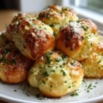 A close-up of freshly baked, golden brown Garlic Knots piled high and topped with melted butter, parsley, and Parmesan cheese.
