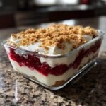 A layered Cherry Cheesecake Trifle featuring graham cracker crust, cream cheese filling, cherry topping, and whipped cream.