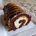 A cross-section view of the Chocolate Caramel Cake Roll showing rich chocolate cake, cream filling, and caramel drizzle.