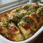 Close-up of baked Garlic Parmesan Pull Apart Bread, cut into squares and topped with cheese and fresh parsley.