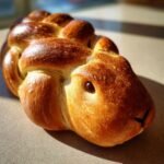Close-up of a beautifully baked Greek Easter Bunny Bread with a shiny, golden-brown crust and raisin eyes.