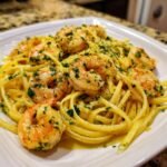 A close-up of a serving of Lemon Butter Garlic Shrimp Pasta tossed in a rich sauce and topped with fresh parsley.