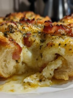 Close-up of an Ooey Gooey Garlic Butter Bacon Ranch Pizza Roll cut open showing melted cheese.